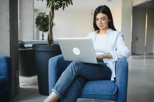 sonriente niña estudiante estudiar en línea con skype maestro, contento joven mujer aprender idioma escucha conferencia reloj seminario web escribir notas Mira a ordenador portátil sentar en cafetería, distante educación foto