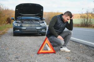 Man with broken car in the middle of the road. photo