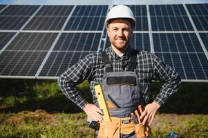 Male worker in uniform outdoors with solar batteries at sunny day. photo