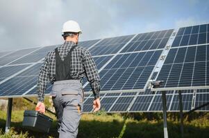 Professional worker installing solar panels on the metal construction, using different equipment, wearing helmet. Innovative solution for energy solving. Use renewable resources. Green energy. photo