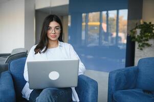 hermosa joven persona de libre dedicación mujer utilizando ordenador portátil computadora sentado a café mesa. contento sonriente niña trabajando en línea o estudiando y aprendizaje mientras utilizando cuaderno. Lanza libre trabajar, negocio personas concepto. foto