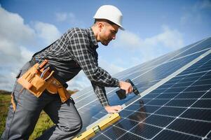 Male worker in uniform outdoors with solar batteries at sunny day. photo