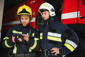 Portrait of two firefighters in fire fighting operation, fireman in protective clothing and helmet using tablet computer in action fighting photo