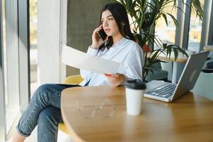 hermosa joven persona de libre dedicación mujer utilizando ordenador portátil computadora sentado a café mesa. contento sonriente niña trabajando en línea o estudiando y aprendizaje mientras utilizando cuaderno. Lanza libre trabajar, negocio personas concepto. foto