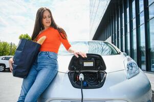 Woman charging electro car at the electric gas station photo