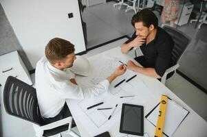 dos personas sentar en frente de construcción plan y hablar acerca de el arquitectura foto