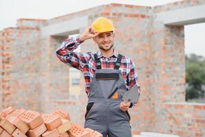 construcción masón trabajador albañil instalando rojo ladrillo con paleta masilla cuchillo al aire libre. foto