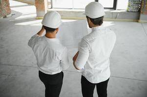 masculino arquitecto dando instrucciones a su capataz a construcción sitio. foto