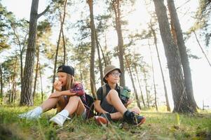 boy and girl go hiking with backpacks on forest road bright sunny day photo