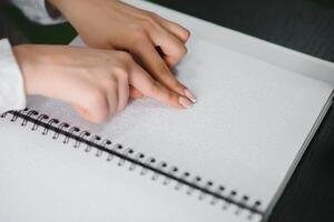ciego mujer leer libro escrito en braille. cerca arriba dedo toque a braille código foto