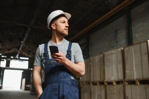 Smiling and happy employee. Industrial worker indoors in factory. Young technician with white hard hat. photo