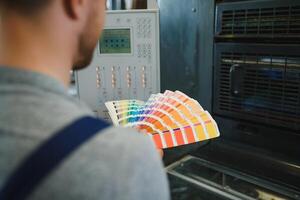 Man working in printing house with paper and paints photo