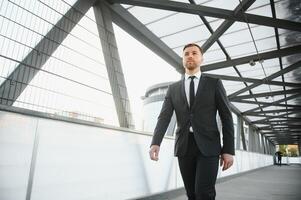 corredor de valores cerca el oficina. un exitoso y avanzado hermoso negocio hombre en un traje mira arriba en frente de él en pie en el antecedentes de hormigón pasos. foto