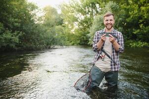 pescador con mosca participación trucha fuera de el agua foto