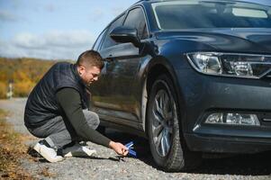 Man with broken down car flat tire in the middle of the street photo