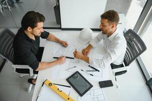 dos personas sentar en frente de construcción plan y hablar acerca de el arquitectura foto