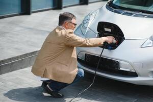 hombre participación poder conector para eléctrico coche foto