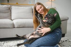 Female owner playing with joyful dog at home. Playing with dog concept photo