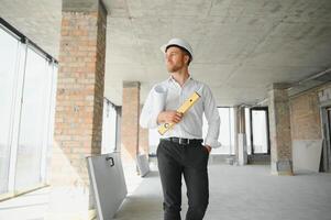 retrato de un arquitecto constructor estudiando diseño plan de el habitaciones, grave civil ingeniero trabajando con documentos en construcción sitio, edificio y hogar renovación, profesional capataz a trabajar. foto