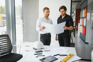 ingeniero o arquitecto trabajo en equipo trabajando en construcción proyecto con edificio modelo y Plano en oficina. construcción concepto. foto