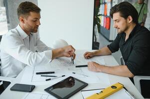 dos personas sentar en frente de construcción plan y hablar acerca de el arquitectura foto