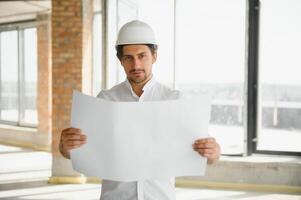 retrato de un arquitecto constructor estudiando diseño plan de el habitaciones, grave civil ingeniero trabajando con documentos en construcción sitio, edificio y hogar renovación, profesional capataz a trabajar. foto