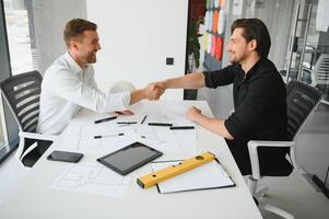 Two colleagues discussing data working on architectural project at construction site at desk in office photo