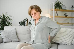 mature lady sitting on bed and touching her back, radiculitis and pain photo