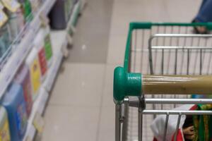 Empty green shopping cart in supermarket aisle photo