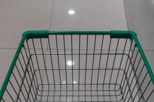 Empty green shopping cart in supermarket aisle photo