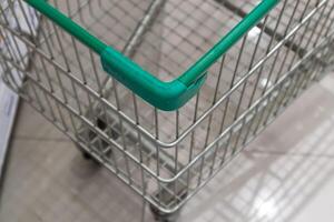Empty green shopping cart in supermarket aisle photo