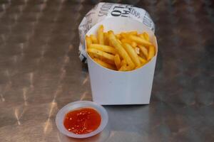 Close up view of French fries and chili sauce on the metal table photo