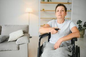 woman in wheelchair uses a tv remote control. photo