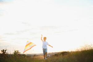 Boy is running with a kite during the day in the field photo