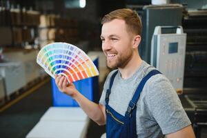 Man working in printing house with paper and paints photo