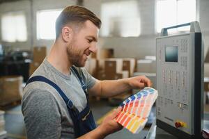 Man working in printing house with paper and paints photo