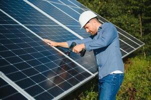 Worker technician connecting heavy solar photo voltaic panels to high steel platform. Exterior solar system installation, alternative renewable green energy generation concept