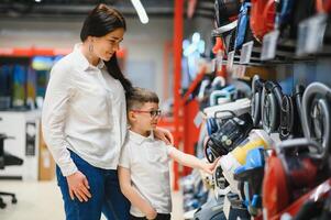 Mother and son shopping for electric vacuum cleaner, smiling photo