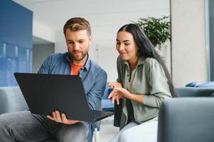 sonriente gente de negocios trabajo colaborar en computadora, idea genial terminado empresa puesta en marcha a oficina reunión. motivado diverso colegas Mira a ordenador portátil pantalla discutir negocio proyecto ideas juntos foto