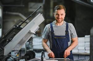 Man working in printing house with paper and paints photo