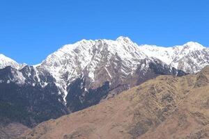 Snow on the Mountains Peak and Blue Sky and tree in India photo