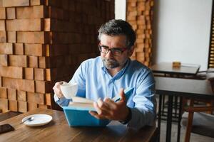 maduro hermoso hombre leyendo un libro en un café foto