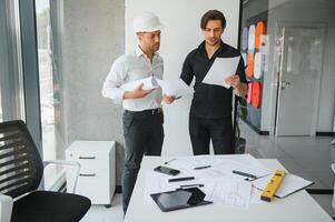 ingeniero o arquitecto trabajo en equipo trabajando en construcción proyecto con edificio modelo y Plano en oficina. construcción concepto. foto