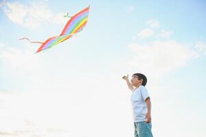 Boy is running with a kite during the day in the field photo