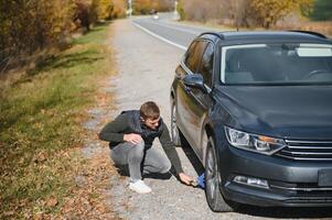 Man with broken down car flat tire in the middle of the street photo