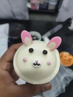 a hand holding a cupcake with a bunny face on it photo