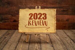 2023 year review - easel sign with antique paper against rustic wood, end of year business concept photo