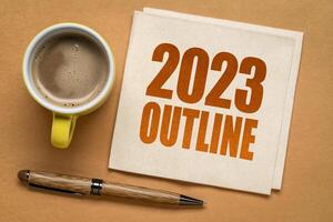 2023 year outline text on a napkin with a cup of coffee, end of year business review concept photo