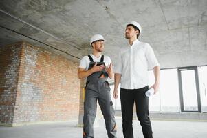 Engineer and worker checking project at building site background, construction site at sunset in evening time photo