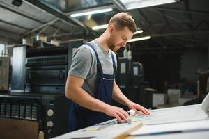 Man working in printing house with paper and paints photo